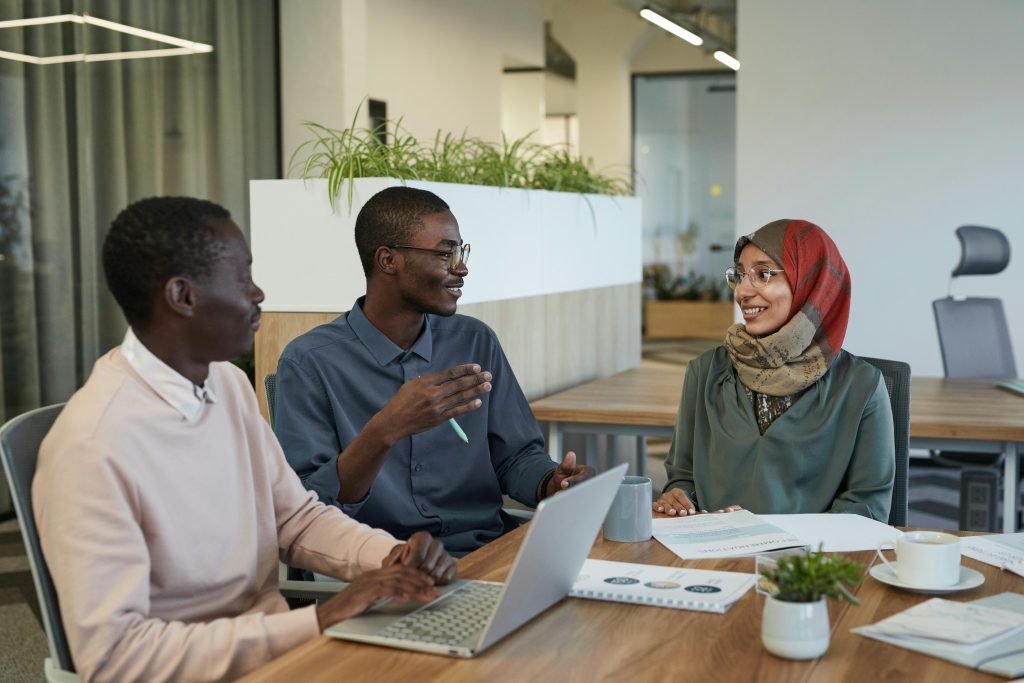 Three colleagues engaged in a collaborative discussion around a table in a modern office setting.